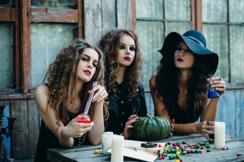 three witches are sitting at the table and prepared the potion on the eve of Halloween